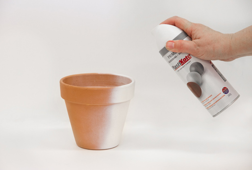 Terracotta pots being primed in Twist & Spray Primer in White